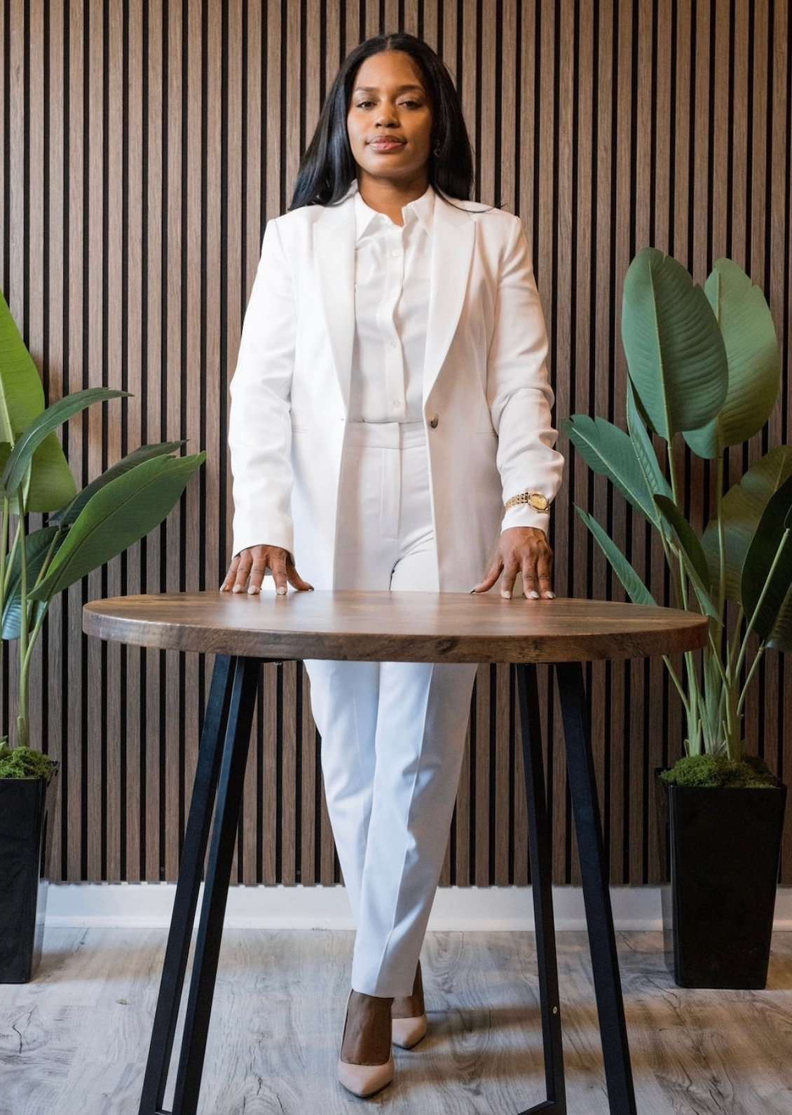 Coach Adanna Clarke in a white suit standing at a table